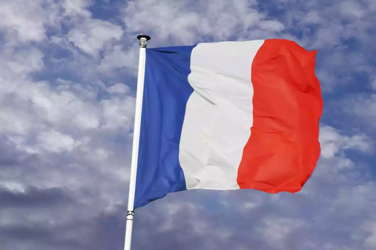 Bandera ondeante de Francia sobre un fondo de cielo azul