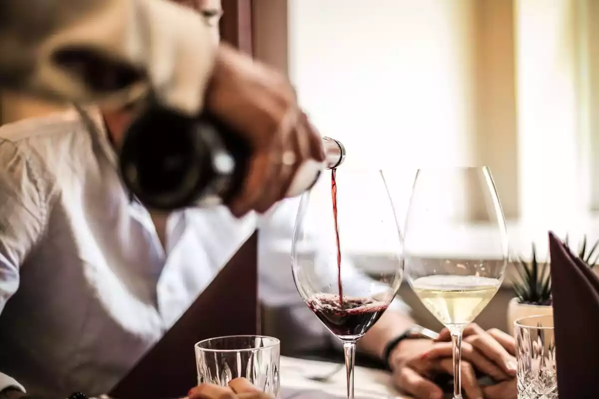 Camarero sirviendo una copa de vino a una pareja en un restaurante