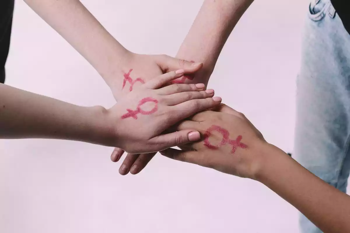 Gente juntando manos con el símbolo feminista