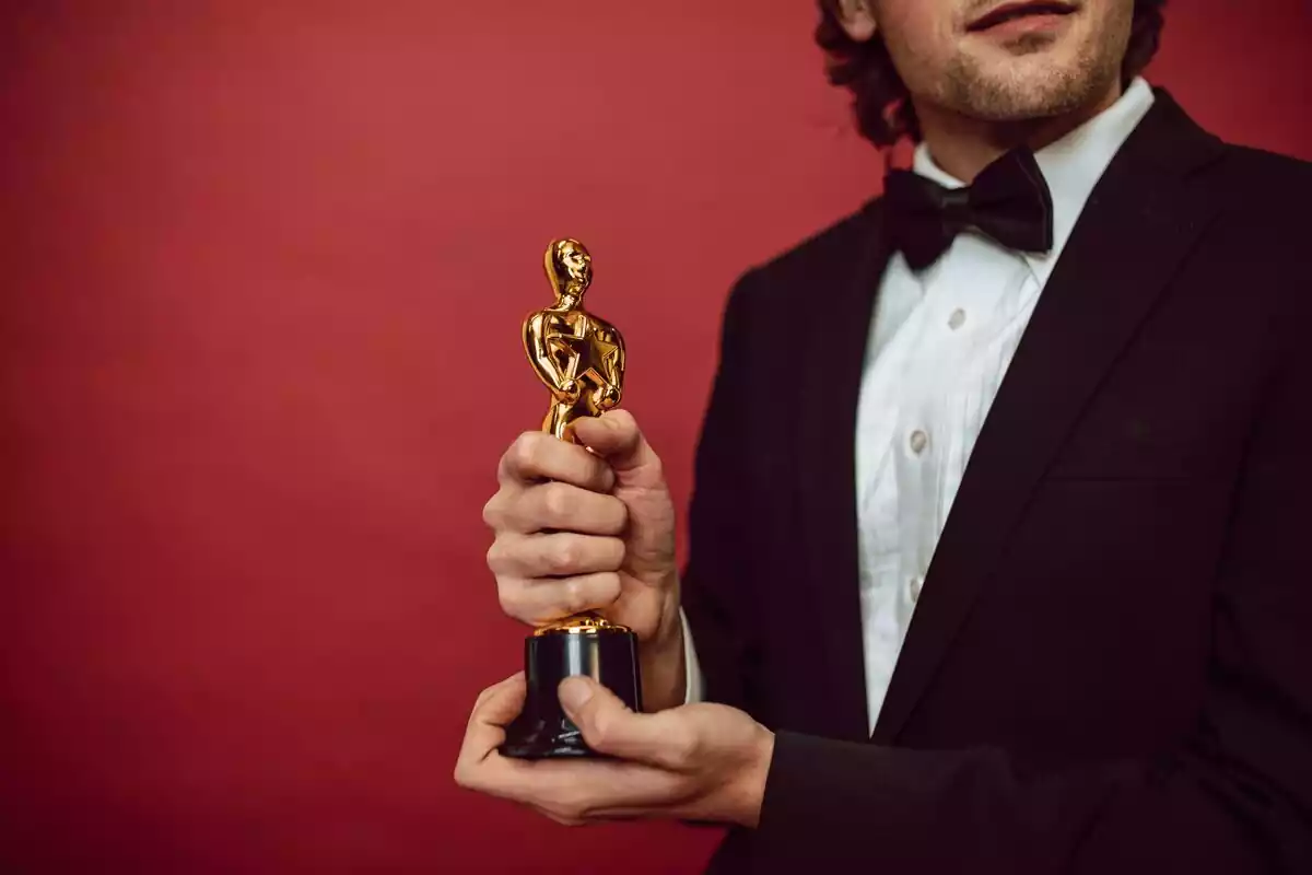 Hombre con la estatuilla de un premio Oscar en la mano