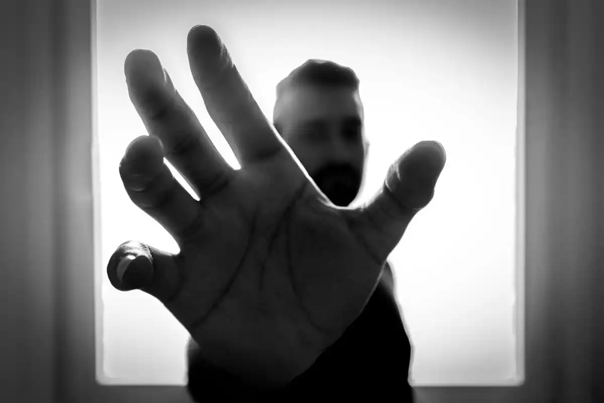 Hombre con la mano abierta en representación de agarrar algo o a alguien con una intención de intimidar