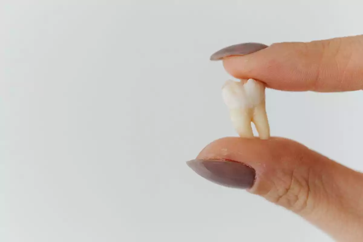 Mujer agarrando con los dedos un diente